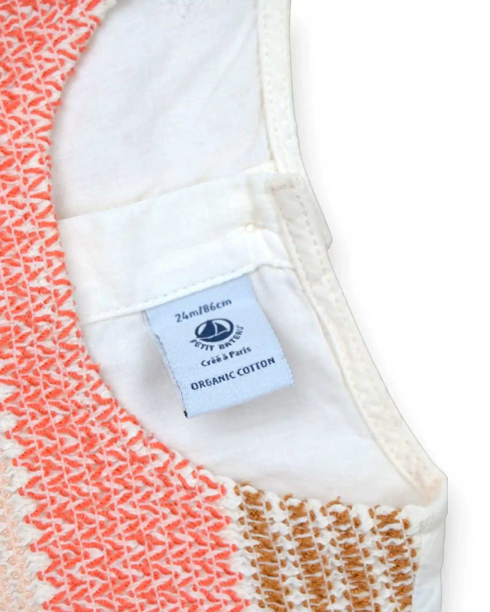 Detalhe de vestido Petit Bateau em algodão orgânico branco com bordado smocking coral e dourado para bebé