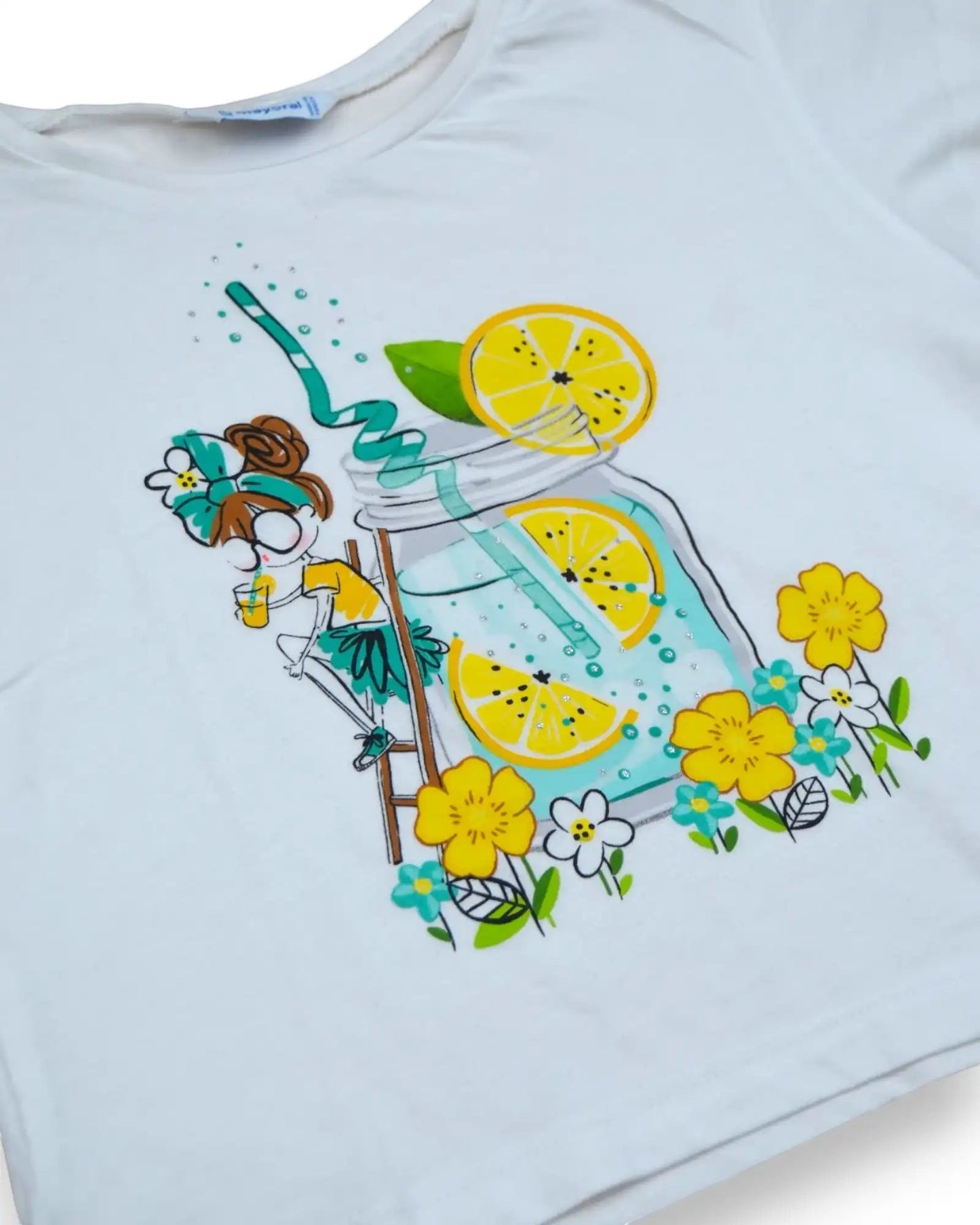 T-shirt branca de manga curta, da Mayoral, estilo cropped, com estampado de limonada e flores. Detalhes em glitter.