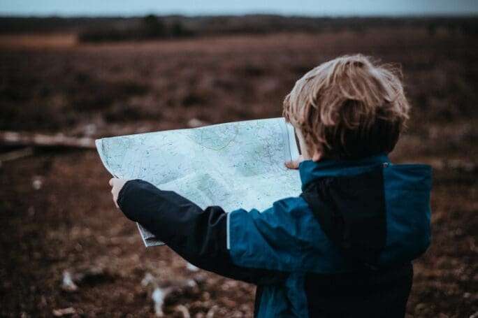 menino louro com mapa na mão - viajar com crianças